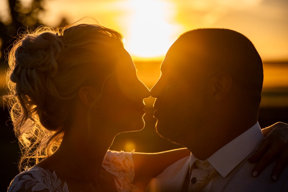 Photo d'un couple de mariés s'embrassant au coucher du soleil