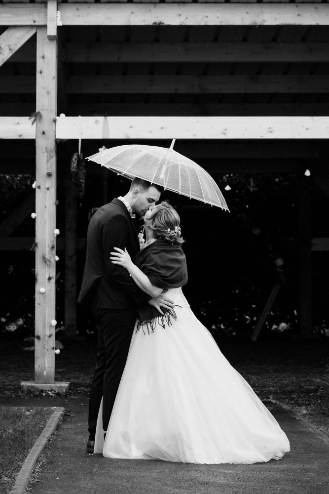 Couple de mariés s'embrassant sous la pluie